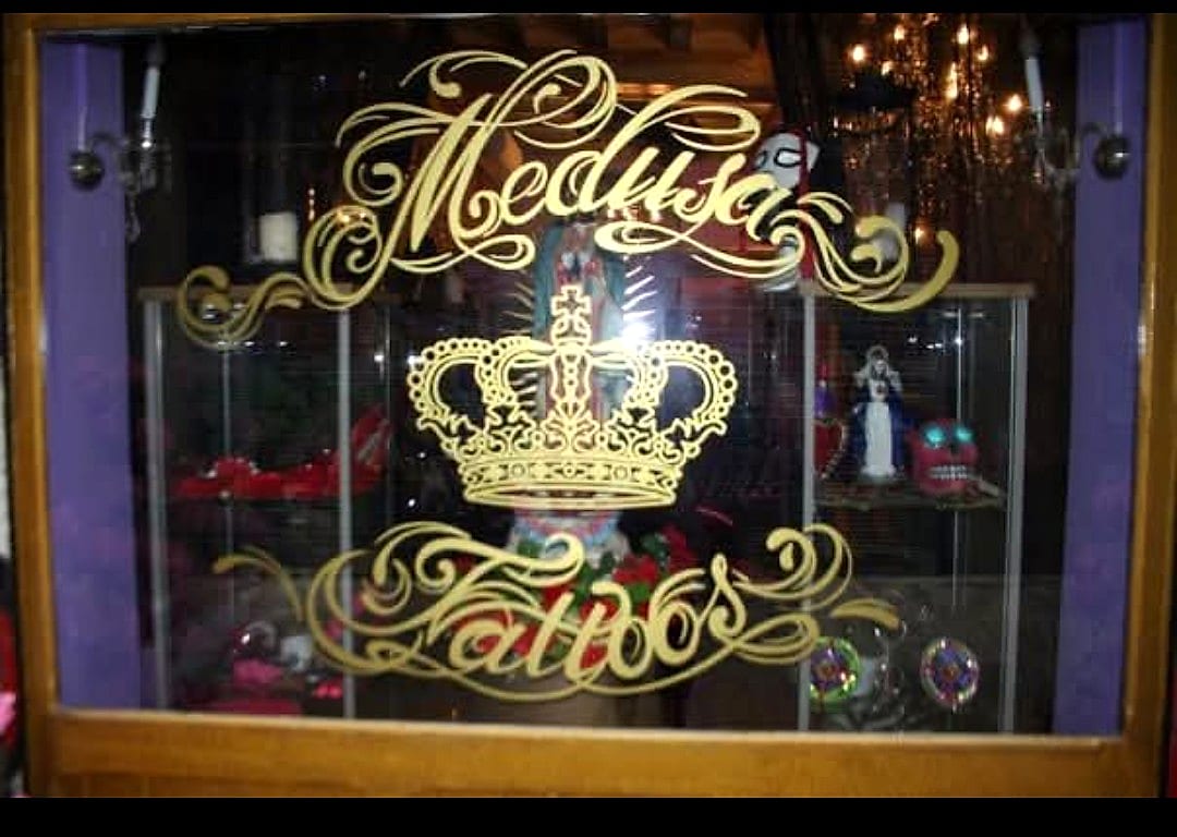 Vetrina Medusa Tattoo con corona dorata affissa sul vetro